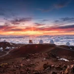 Mauna Kea webcam view showing observatories above clouds during sunset with clear sky and scenic volcanic landscape in Hawaii